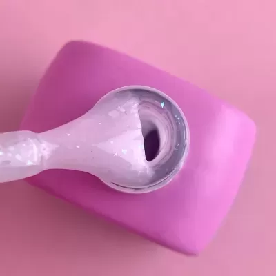 Pincel aplicador com gel transparente e brilhante sobre fundo rosa