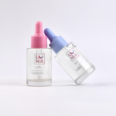 Dois frascos de vidro transparentes com conta-gotas coloridos sobre fundo branco