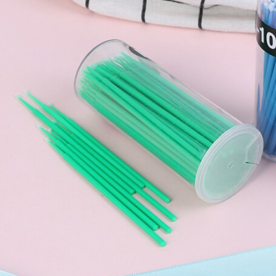 Palitos verdes de plástico em recipiente transparente sobre mesa cor-de-rosa