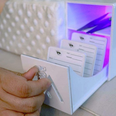 Caixa organizadora branca com cartões etiquetados e mão abrindo à frente com chave