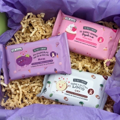 Embalagens coloridas de toalhitas alcoólicas com ilustrações de frutas e texto em espanhol