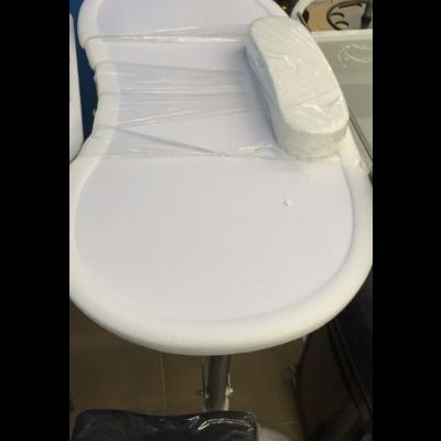 Cama de massagem branca com almofada oval e proteção plástica