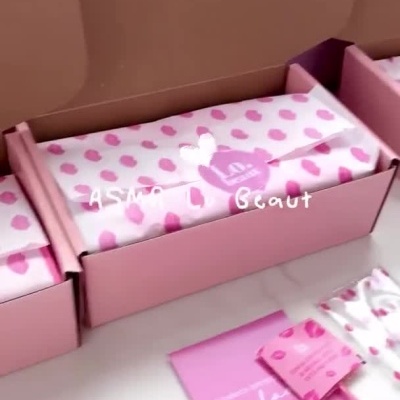 Caixas cor de rosa abertas com produtos de cosmética Lo Beaut e mensagem em cartão