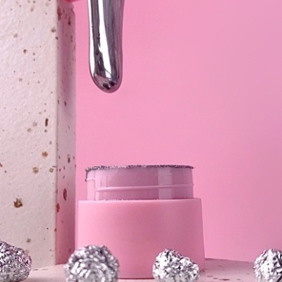 Frasco rosa com tinta prateada brilhante derramando