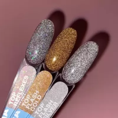 Amostras de verniz de unhas com glitter prateado, dourado e multicolorido em fundo rosa.