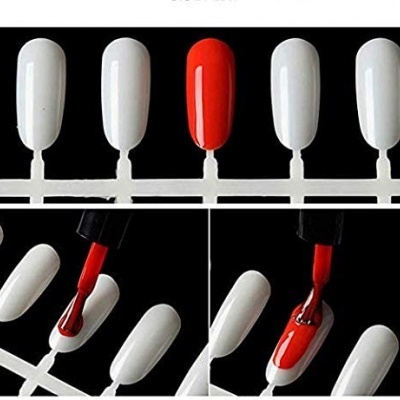 Unhas postiças brancas em fileira com uma pintada de vermelho e aplicação de verniz vermelho.