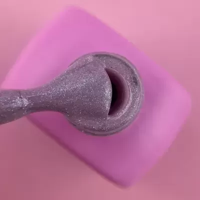 Pincel de verniz lilás brilhante com frasco lilás e fundo rosa