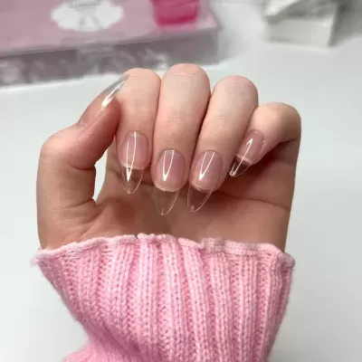 Mão com unhas artificiais transparentes e manga rosa de malha