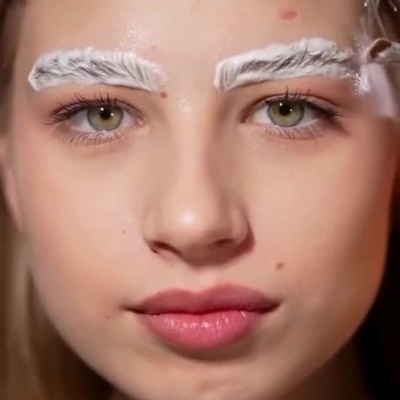 Produto AQUA FLUID MAESTRO com conta-gotas e aplicação nas sobrancelhas da modelo.