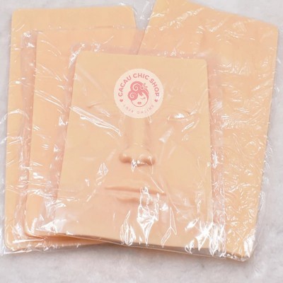 Produto de silicone cor pele com formato facial embalado em plástico com etiqueta rosa