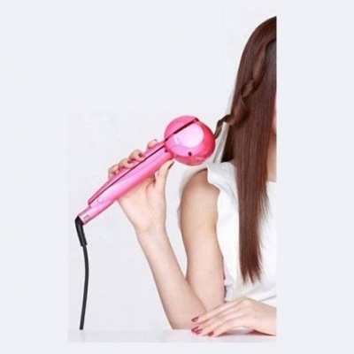 Modelador de cabelo automático cor de rosa, usado por mulher com cabelo castanho e fundo branco