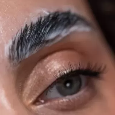 Close-up de olho castanho com sobrancelha com produto branco