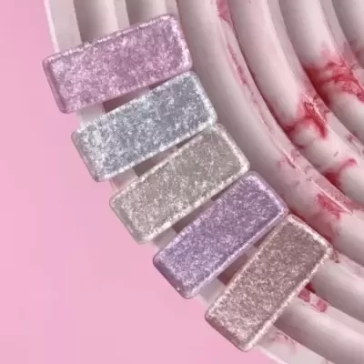 Presilhas retangulares de veludo em tons pastel sobre prato marmoreado.