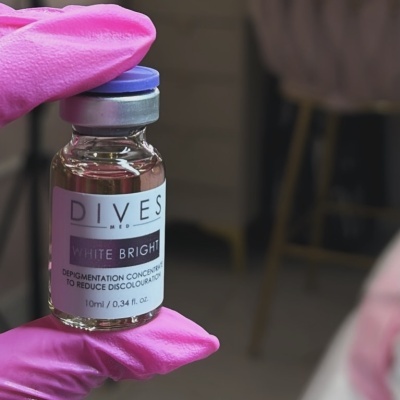 Frasco de vidro com rótulo DIVES MED WHITE BRIGHT e luva rosa