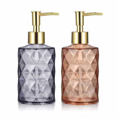 Dois dispensadores de sabonete líquidos em vidro com padrão facetado e tampa dourada