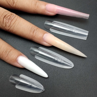 Mão com unhas postiças alongadas coloridas e moldes transparentes em superfície preta