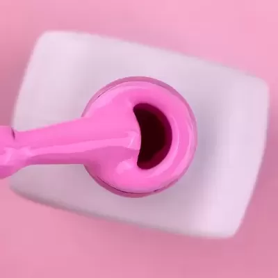 Frasco aberto de verniz rosa com pincel e verniz visível