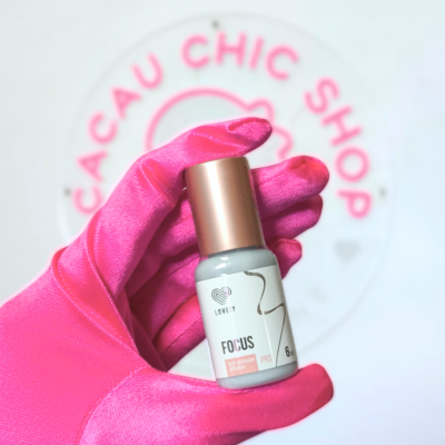 Frasco branco e dourado com rótulo FOCUS PRO segurado por mão com luva rosa