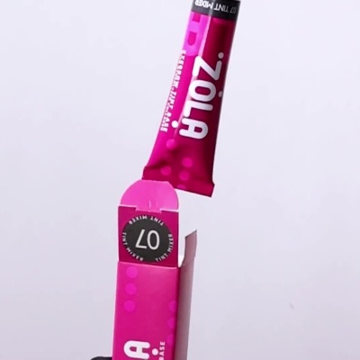Embalagem e tubo do ZOLA 07 Tint Mixer com amostra de tinta vermelha num pincel