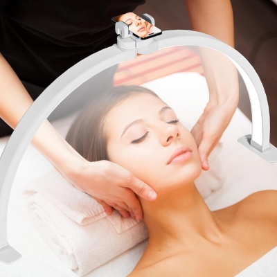 Aro branco com lupa ou espelho pequeno sendo usado numa massagem facial.