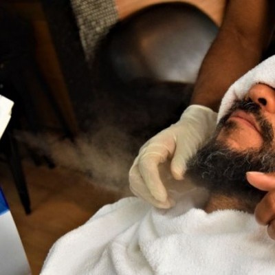 Homem recebendo vapor no rosto com toalha nos olhos