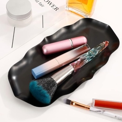 Bandeja preta com pincel de maquilhagem, batom rosa e gloss labial em superfície branca