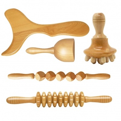 Conjunto de instrumentos de massagem em madeira clara sobre fundo branco