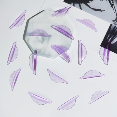 Peças semicirculares de plástico roxo translúcido sobre superfície branca com prato transparente e papel fotográfico preto e branco