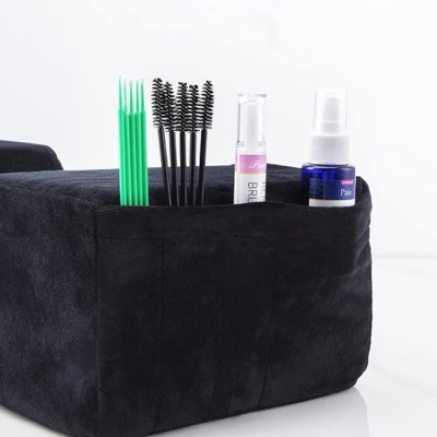 Organizador preto com escovas de cílios, aplicadores verdes, batom e frasco azul.