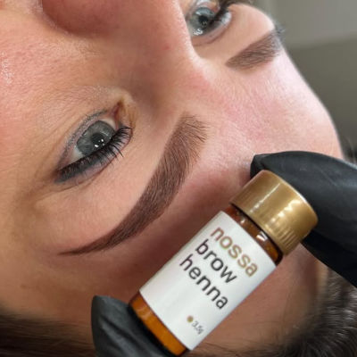 Frasco da Nossa Brow Henna perto das sobrancelhas de uma pessoa