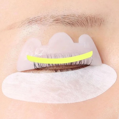 Adesivo de silicone transparente sobre pestanas com linha amarela e algodão branco abaixo do olho