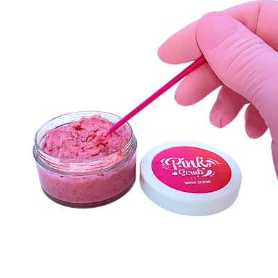Frasco de creme esfoliante rosa com tampa branca e mão com luva rosa a mexer no creme.