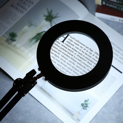 Lâmpada de leitura com lente de aumento sobre revista aberta