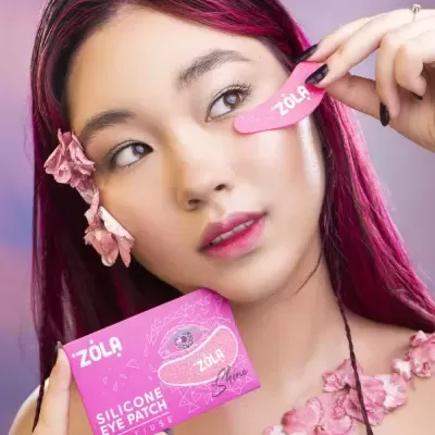 Mulher segurando patch de silicone rosa para olhos e caixa rosa com texto ZOLA Silicone Eye Patch