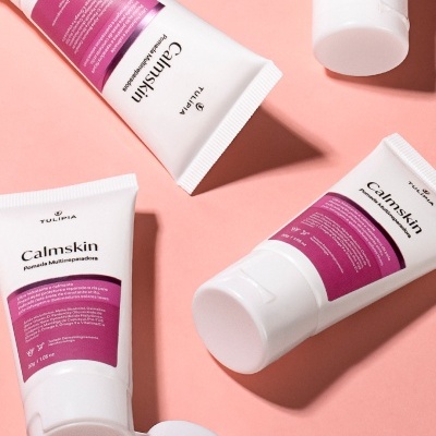 Tubos de creme Calmskin Tulipia com etiqueta roxa sobre fundo rosa