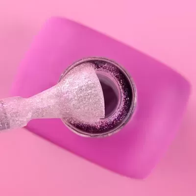 Verniz de unhas glitter rosa aberto com pincel.