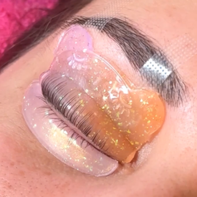 Olho fechado com sobrancelha, fita adesiva prateada e gel pads coloridos com brilho nas pestanas