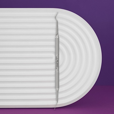 Ferramenta para unhas metálica com texto STALEKS PRO EXPERT 201 T sobre suporte branco com linhas curvas e fundo roxo