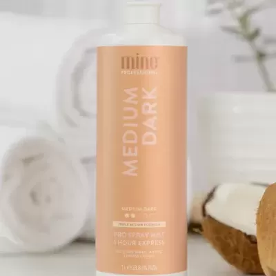 Frasco de produto para bronzeamento em spray com fundo branco e toalhas.