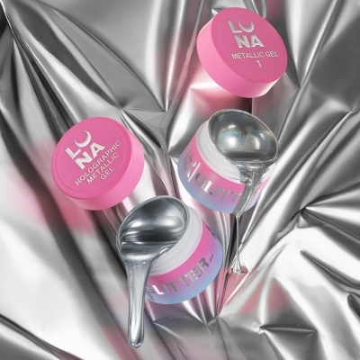 Frascos de gel holográfico metálico LO NA com tampas rosas sobre tecido metálico prateado