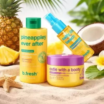 Produtos b.fresh amarelos e azul na areia com abacaxi e coco