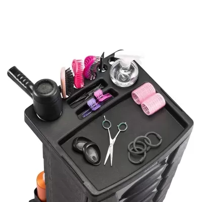 Carrinho de cabeleireiro preto com acessórios como secador, escovas, spray, tesoura e elásticos