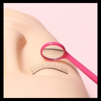 Pestanas falsas pretas com ferramenta rosa e espelho, em fundo rosa