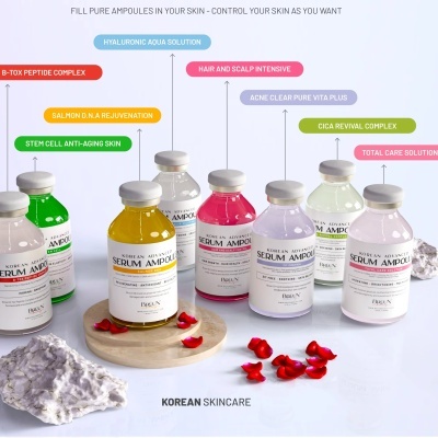 Frascos coloridos de sérum ampolas coreanas em superfície branca com pétalas vermelhas.