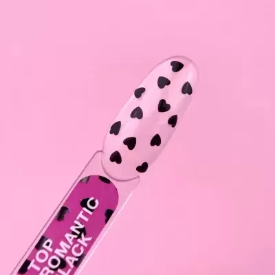 Esponja de unha transparente com corações pretos e texto no cabo em fundo rosa