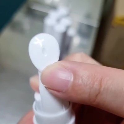 Aplicador branco com base lilás e dispensa líquido transparente