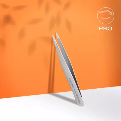 Pinça metálica prata com gravação, fundo laranja com sombra de folhas