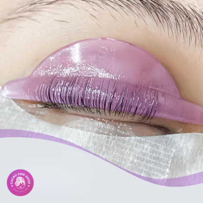 Olho fechado com extensão de pestanas e almofada rosa translúcida sobre a pálpebra