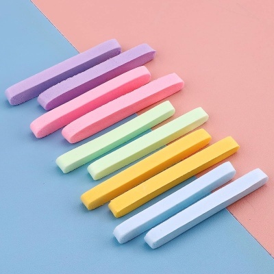 Barras de giz colorido em tons pastel sobre fundo azul e rosa