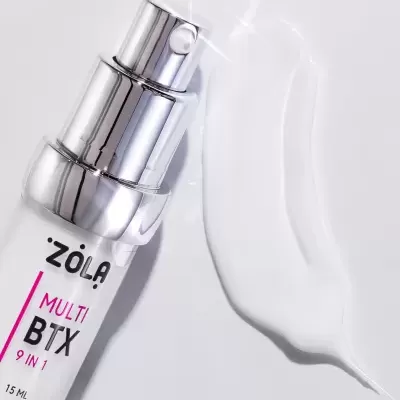 Frasco de spray branco com tampa metálica prateada e texto ZOLA MULTI BTX 9 IN 1 15 ML sobre superfície branca com líquido